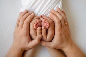 A pair of hands gently cradling a baby's tiny feet, providing affordable IVF care.