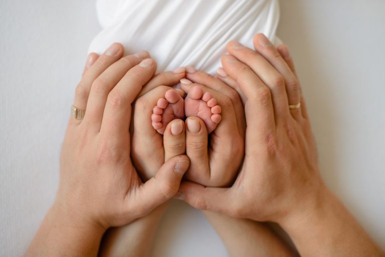 A pair of hands gently cradling a baby's tiny feet, providing affordable IVF care.