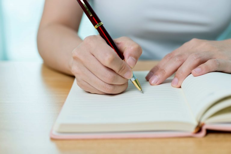 Close-up of a person writing in a notebook, emphasising the importance of staying organised during an IVF journey